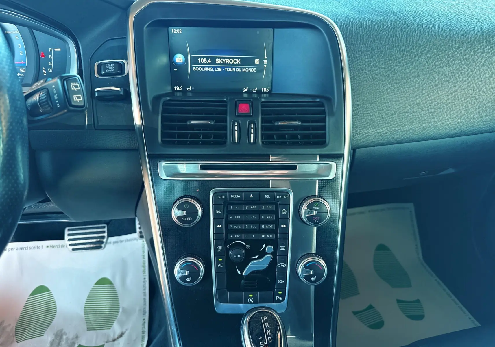Vue rapprochée du tableau de bord et console centrale noire du Volvo XC60 gris, avec écran radio affichant Skyrock.