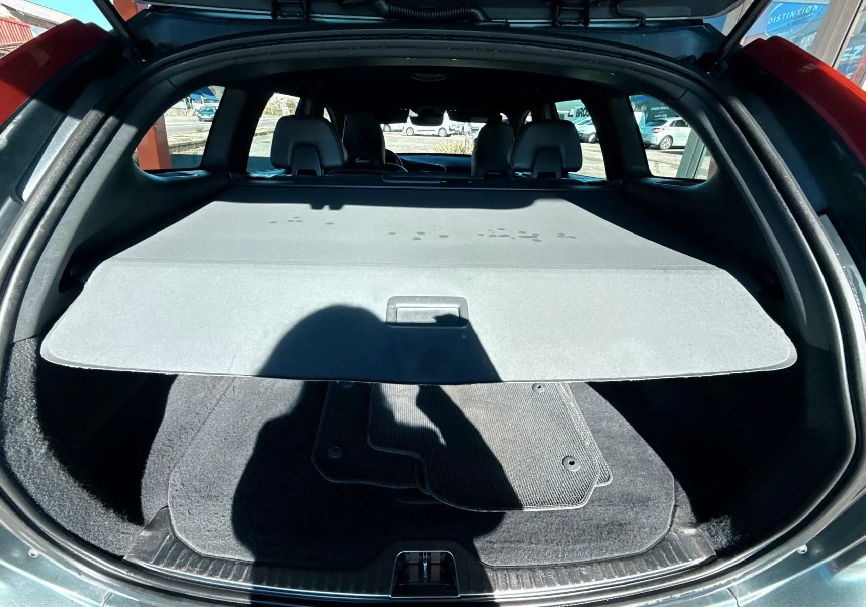 Coffre ouvert d'un Volvo XC60 gris 2016, vue arrière montrant la plage arrière et tapis de sol noir.