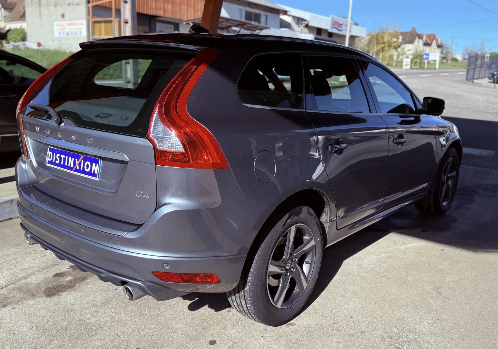 Vue 3/4 arrière droite d'un Volvo XC60 gris métallisé avec feux arrière en forme de L et jantes alliage foncé.