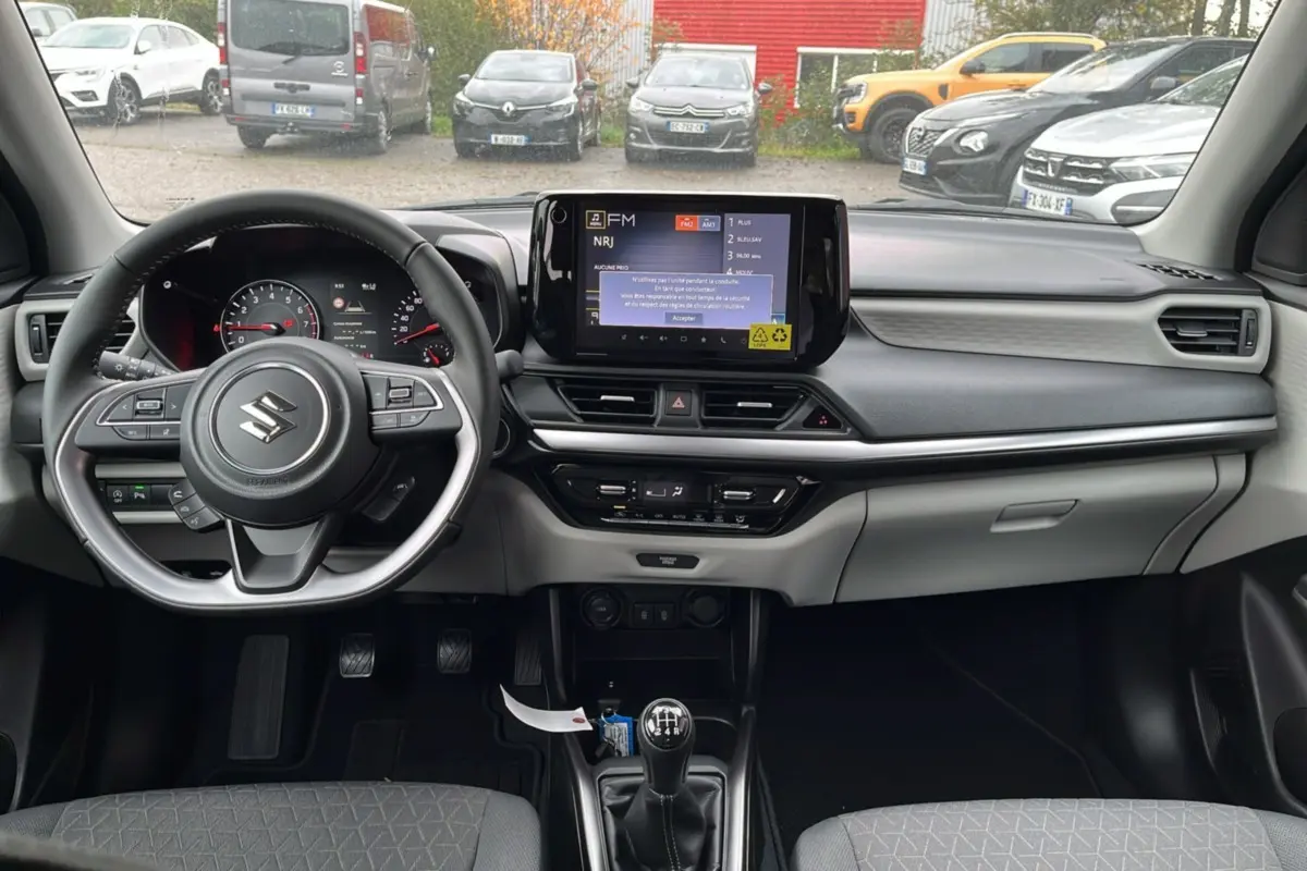 Intérieur de la Suzuki Swift 1.2 Dualjet Hybrid Allgrip Pack 2025, vue frontale du tableau de bord et volant cuir multifonctions.