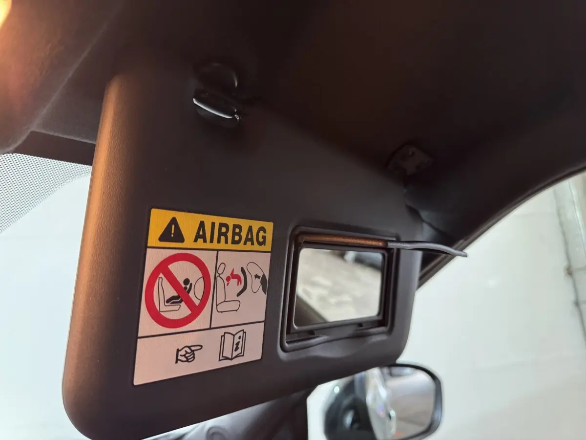 Détail du pare-soleil côté conducteur avec miroir et avertissement airbag dans un Nissan Juke gris clair.