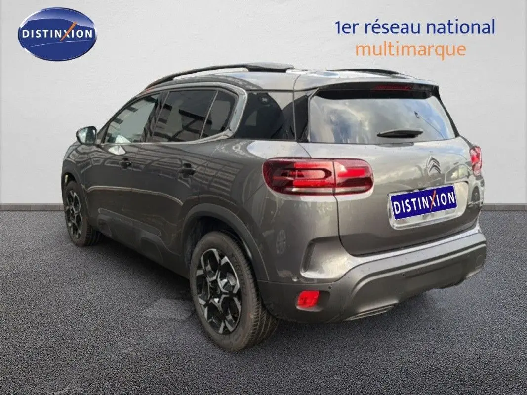 Vue 3/4 arrière droite d’un Citroën C5 Aircross Hybrid gris platinium avec jantes noires bicolores et vitres teintées.