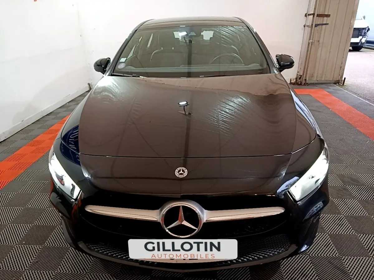 Vue avant d'une Mercedes Classe A 250 e Business Line noire avec phares LED allumés en intérieur.