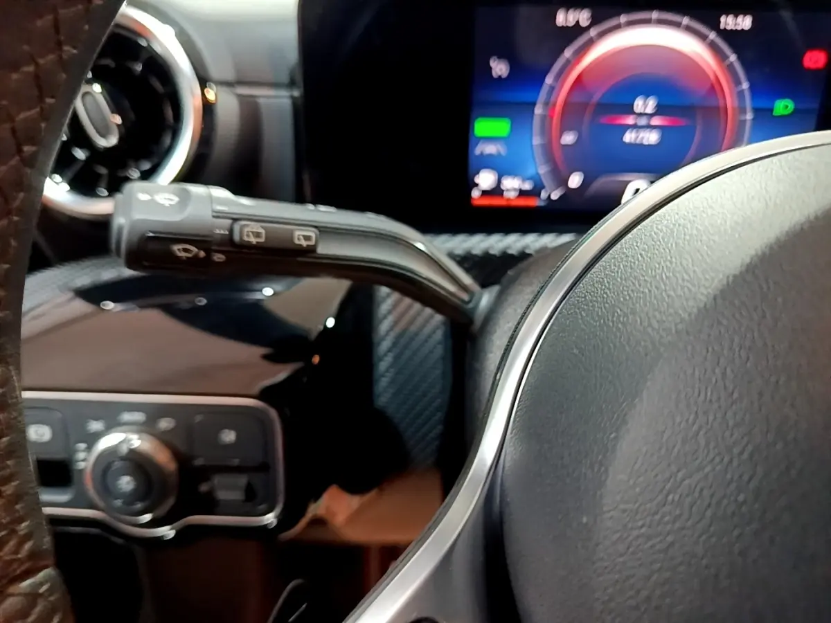 Gros plan intérieur sur le volant et le combiné d'instruments numérique bleu de la Mercedes Classe A noire.