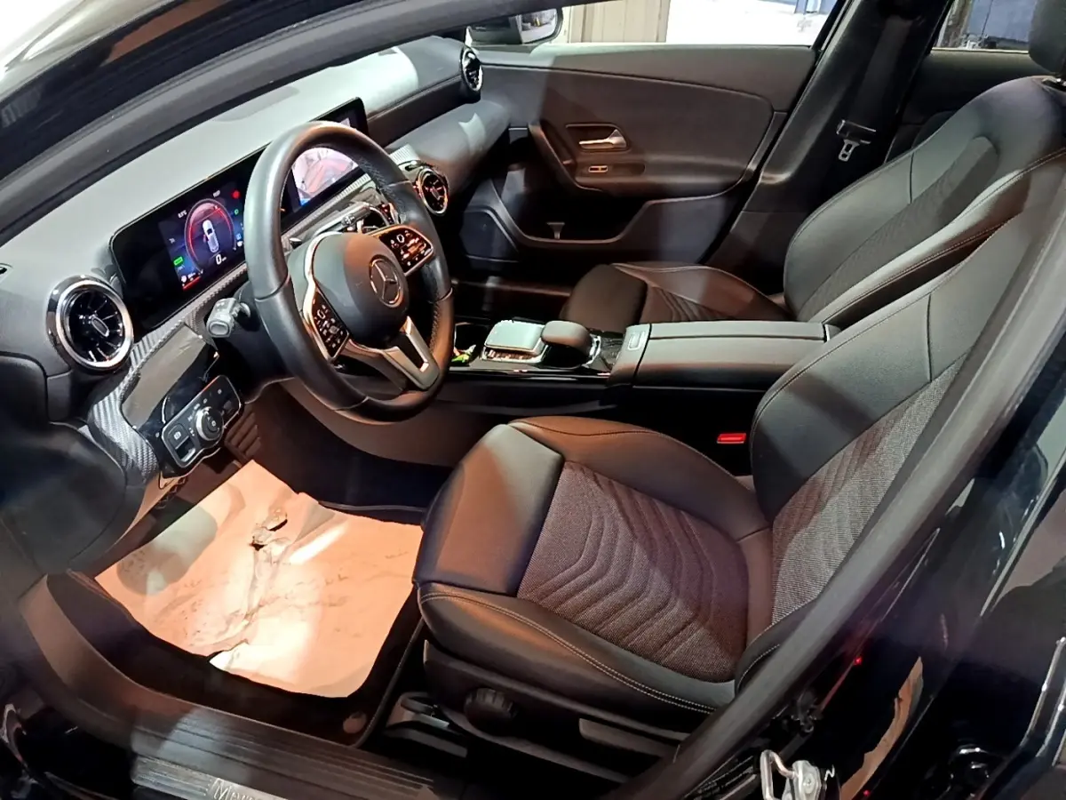 Vue intérieure côté conducteur de la Mercedes Classe A 250 e Business Line noire, avec tableau de bord digital et sièges en cuir.