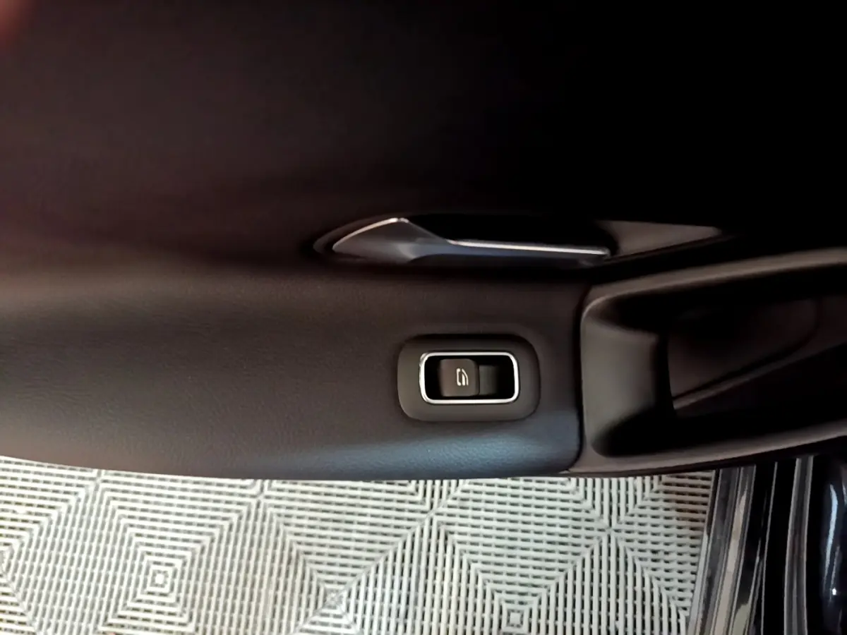 Gros plan sur la poignée intérieure et le bouton de verrouillage de la porte côté gauche d’une Mercedes Classe A noire.