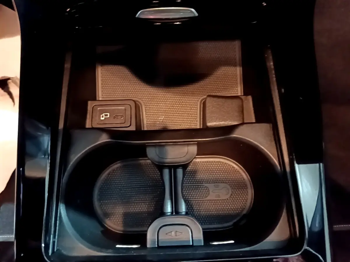 Gros plan sur la console centrale noire de la Mercedes Classe A 250 e Business Line 2020, avec porte-gobelets et chargeur sans fil.