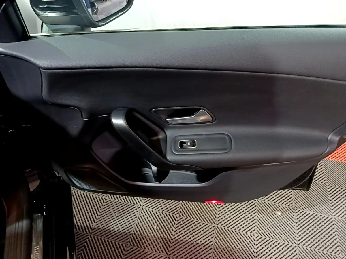 Vue intérieure côté gauche de la porte avant noire d'une Mercedes Classe A 250 e Business Line avec poignée et commande de vitre.
