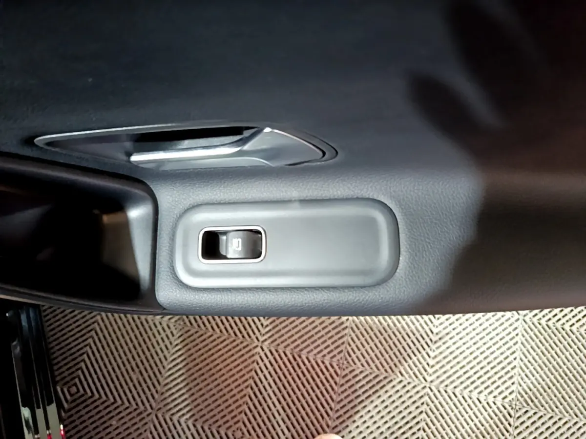 Gros plan sur le bouton de verrouillage des portes intégré dans la garniture intérieure noire d'une Mercedes Classe A 250 e.