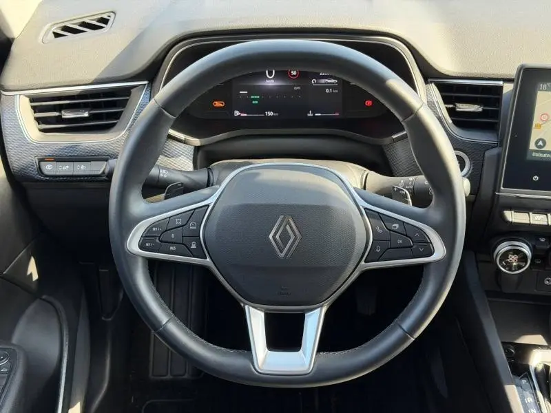 Vue intérieure centrée sur le volant du Renault Arkana 2025, avec tableau de bord numérique et commandes intégrées.
