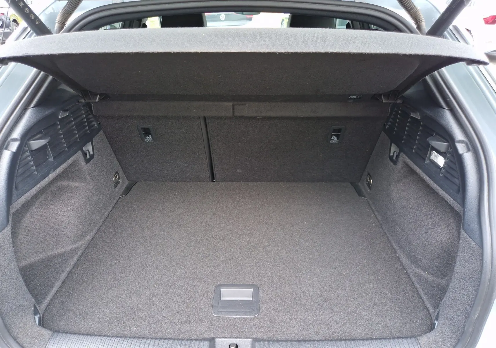 Coffre ouvert vu de l'arrière d'un Audi Q2 35 TFSI 2023 gris flèche, montrant un espace de chargement propre et spacieux.