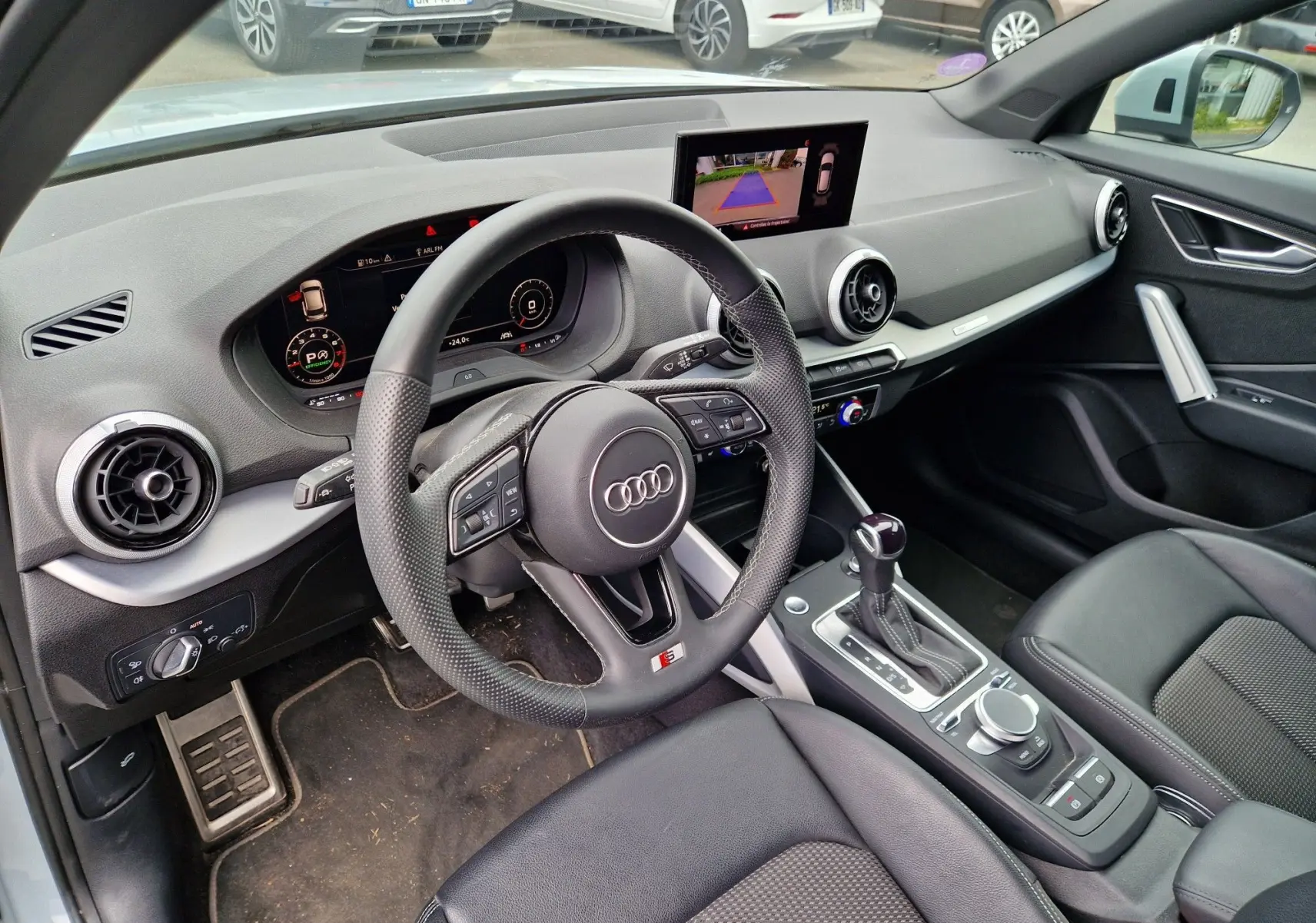 Vue intérieure côté conducteur de l'Audi Q2 35 TFSI 2023, avec volant S line, écran MMI et sellerie noire.
