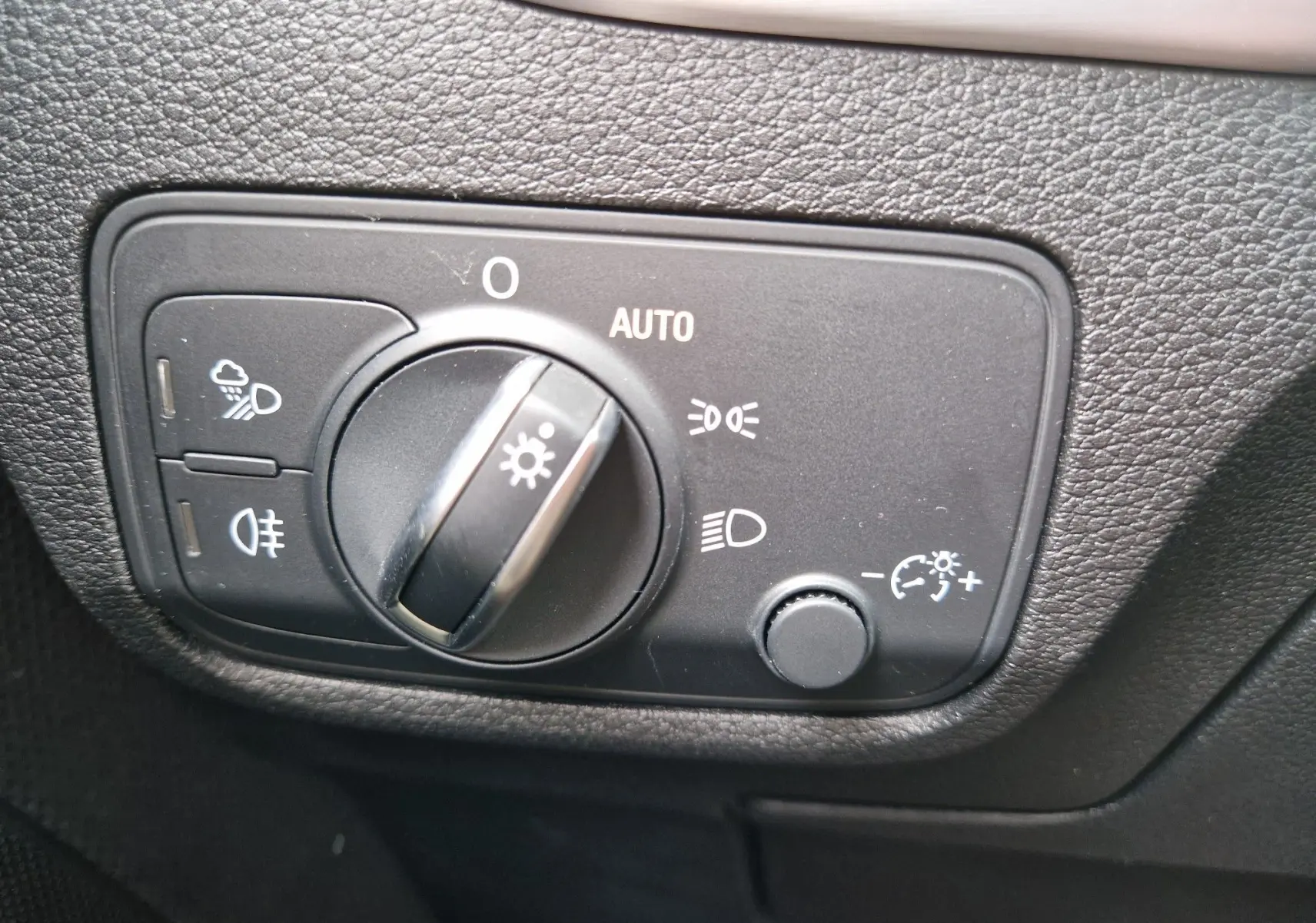 Gros plan sur le bouton de commande des phares dans l’habitacle de l’Audi Q2 35 TFSI gris flèche, finition S line.