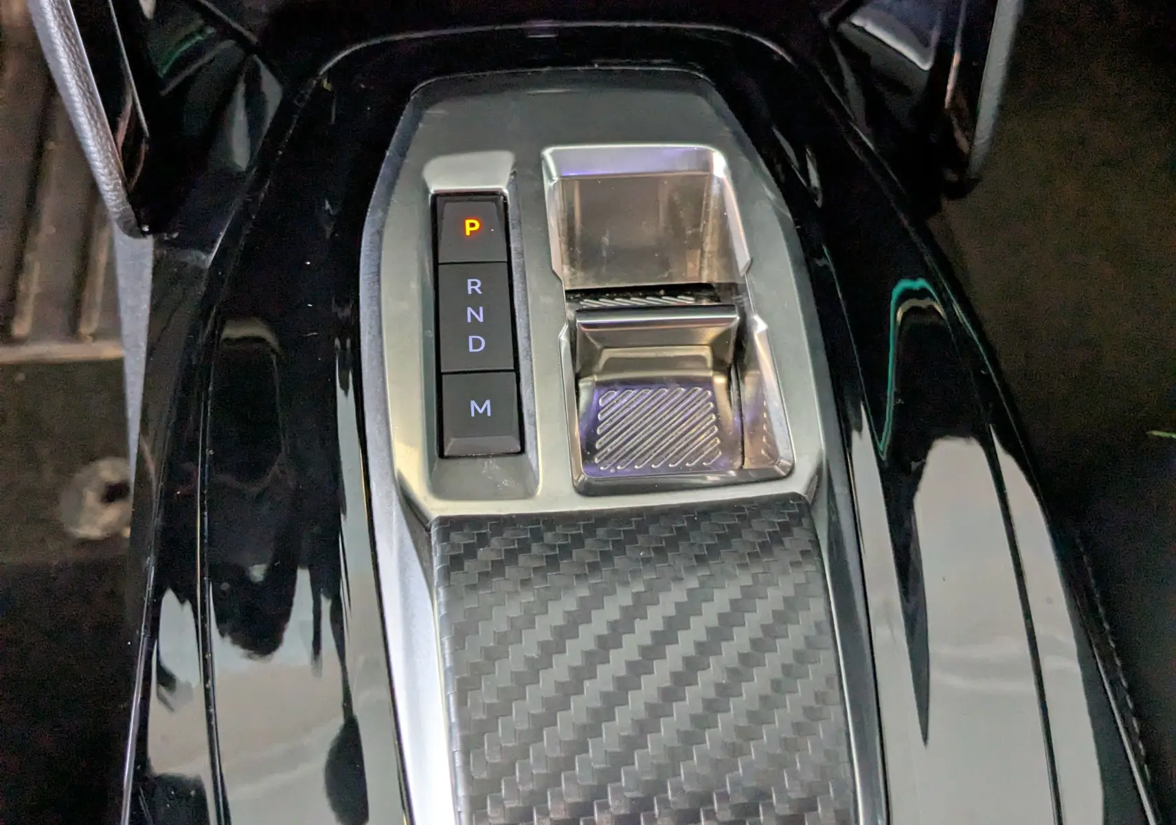 Gros plan sur la console centrale noire brillante avec sélecteur de vitesses électronique du Peugeot 208 Hybrid 145 e-DCS6 GT.