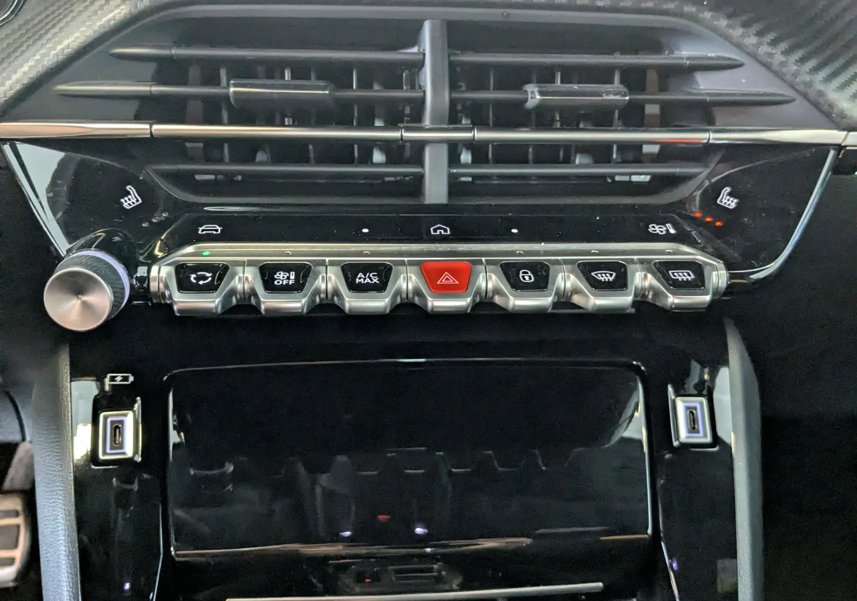 Vue rapprochée de la console centrale du Peugeot 208 Hybrid 145 GT, boutons métalliques et commandes climatisation.