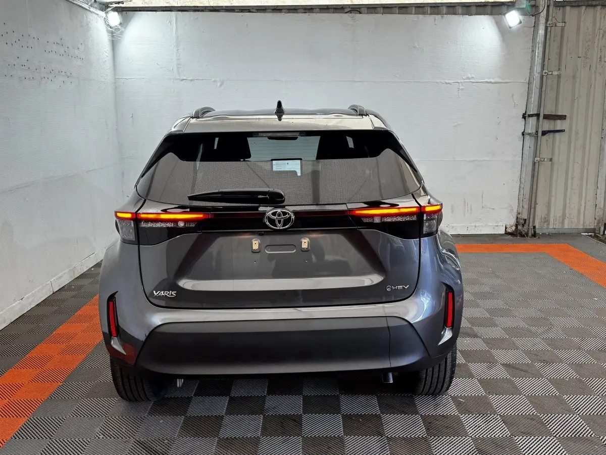 Vue arrière d'une Toyota Yaris Cross gris foncé avec feux LED allumés dans un garage éclairé.