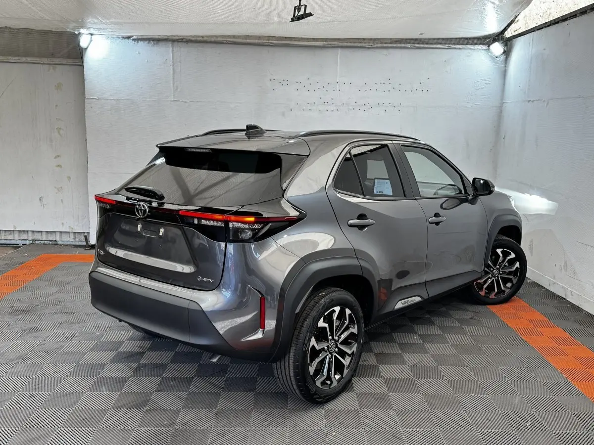 Toyota Yaris Cross gris foncé vue 3/4 arrière droit, avec feux arrière LED et jantes alliage noires.