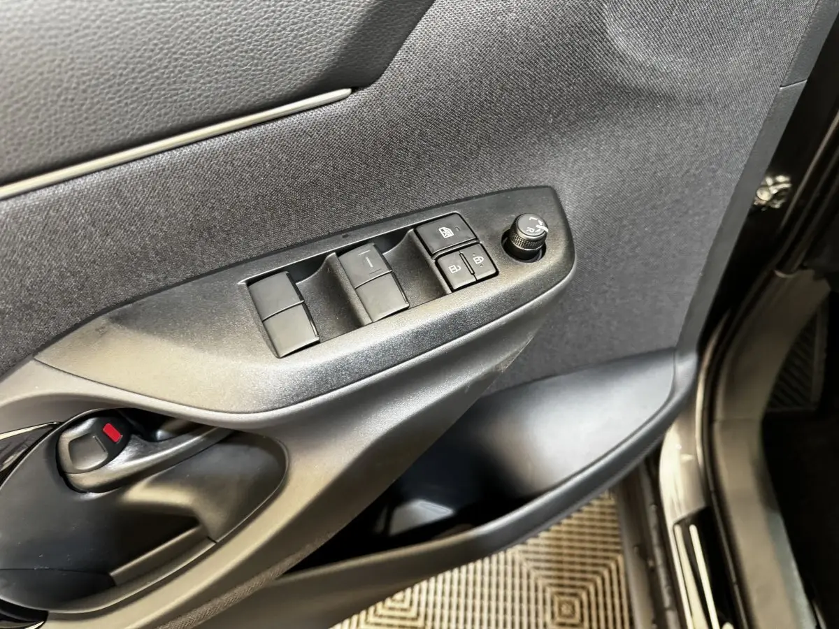 Gros plan sur la porte côté conducteur de la Toyota Yaris Cross gris foncé, avec commandes des vitres et rétroviseurs.