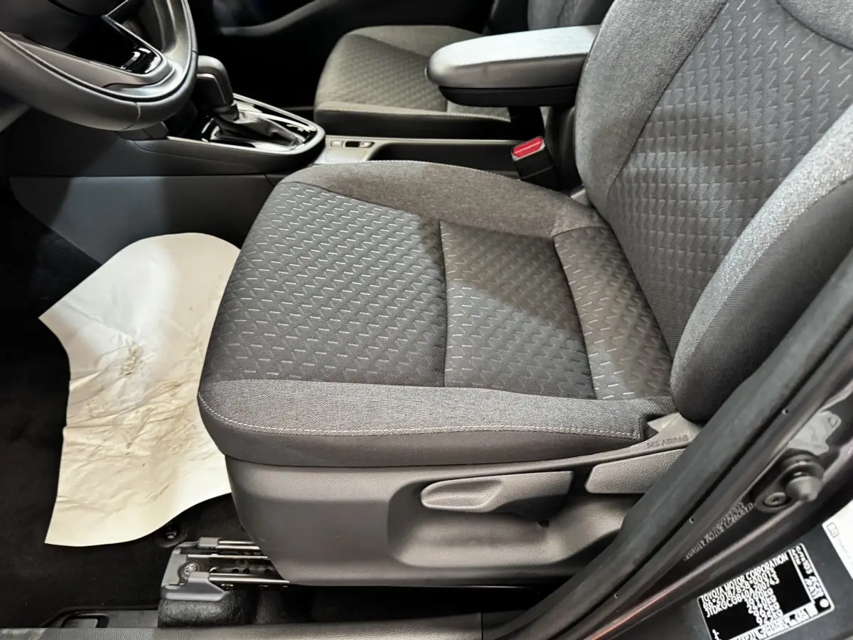 Gros plan sur le siège avant droit gris foncé de la Toyota Yaris Cross 2026, avec accoudoir et levier de boîte automatique visible.