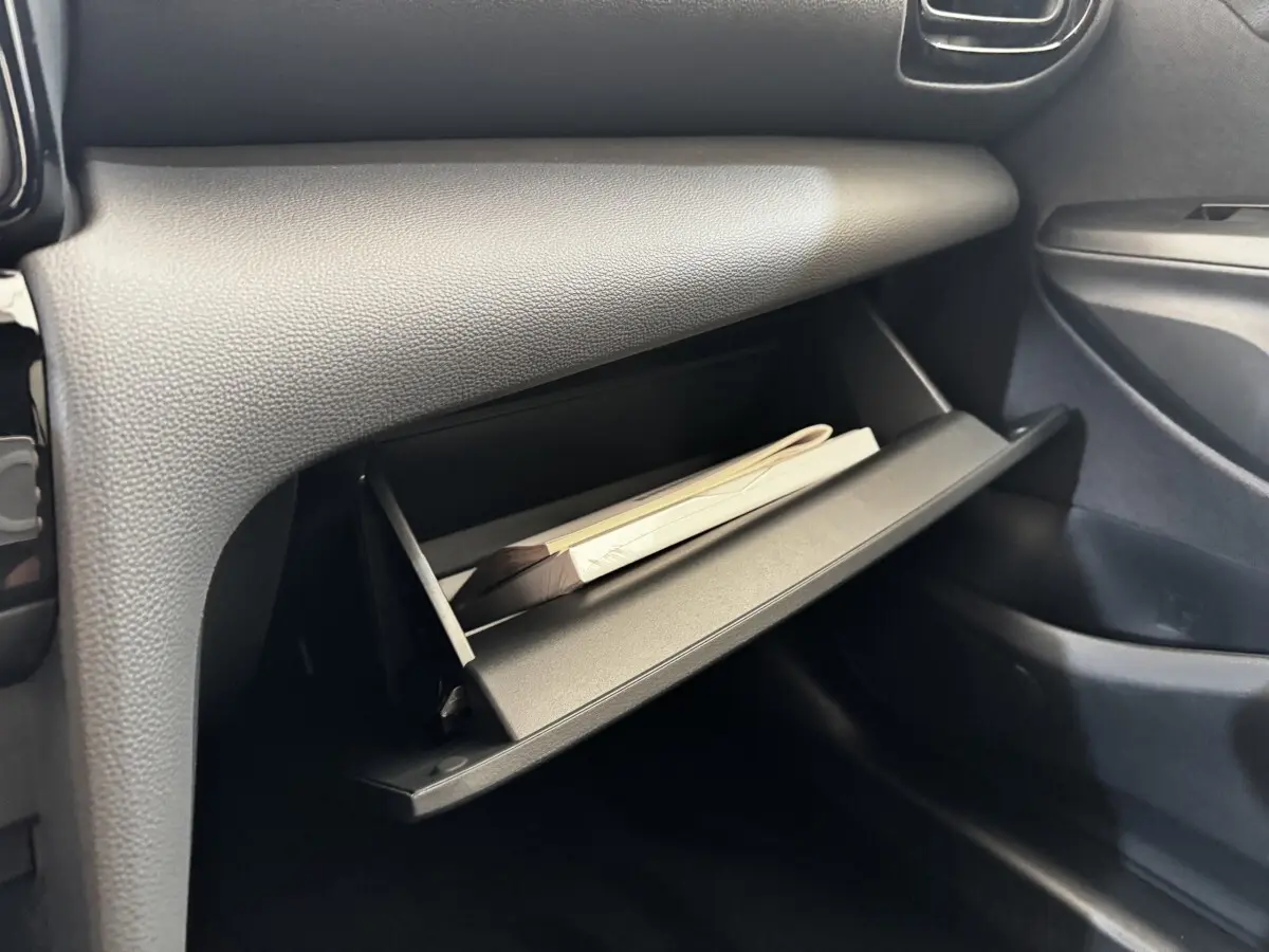 Gant de boîte à gants ouvert côté passager dans l’habitacle gris foncé du Toyota Yaris Cross 2026.