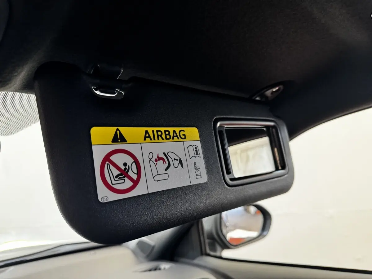 Détail du pare-soleil côté conducteur avec miroir et avertissement airbag dans un Toyota Yaris Cross gris foncé.