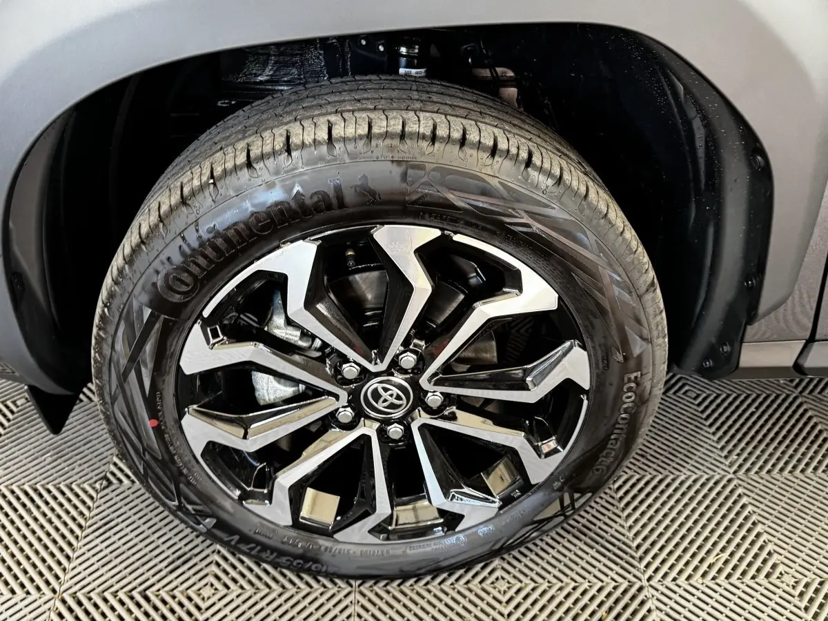 Gros plan sur la roue avant droite du Toyota Yaris Cross gris foncé, jante alliage noire et argentée design moderne.