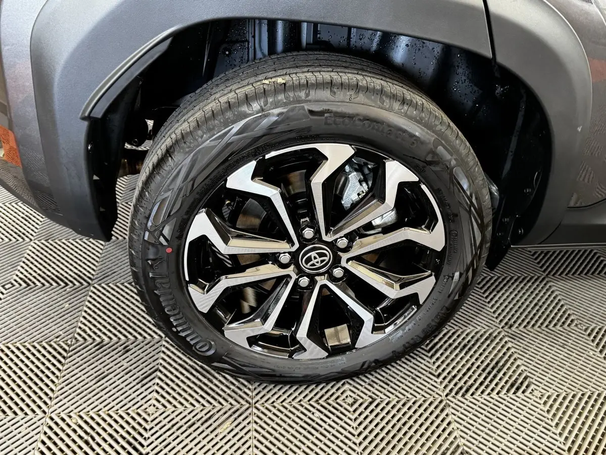 Gros plan sur la roue avant droite du Toyota Yaris Cross gris foncé, mettant en valeur la jante noire et argentée au design moderne.