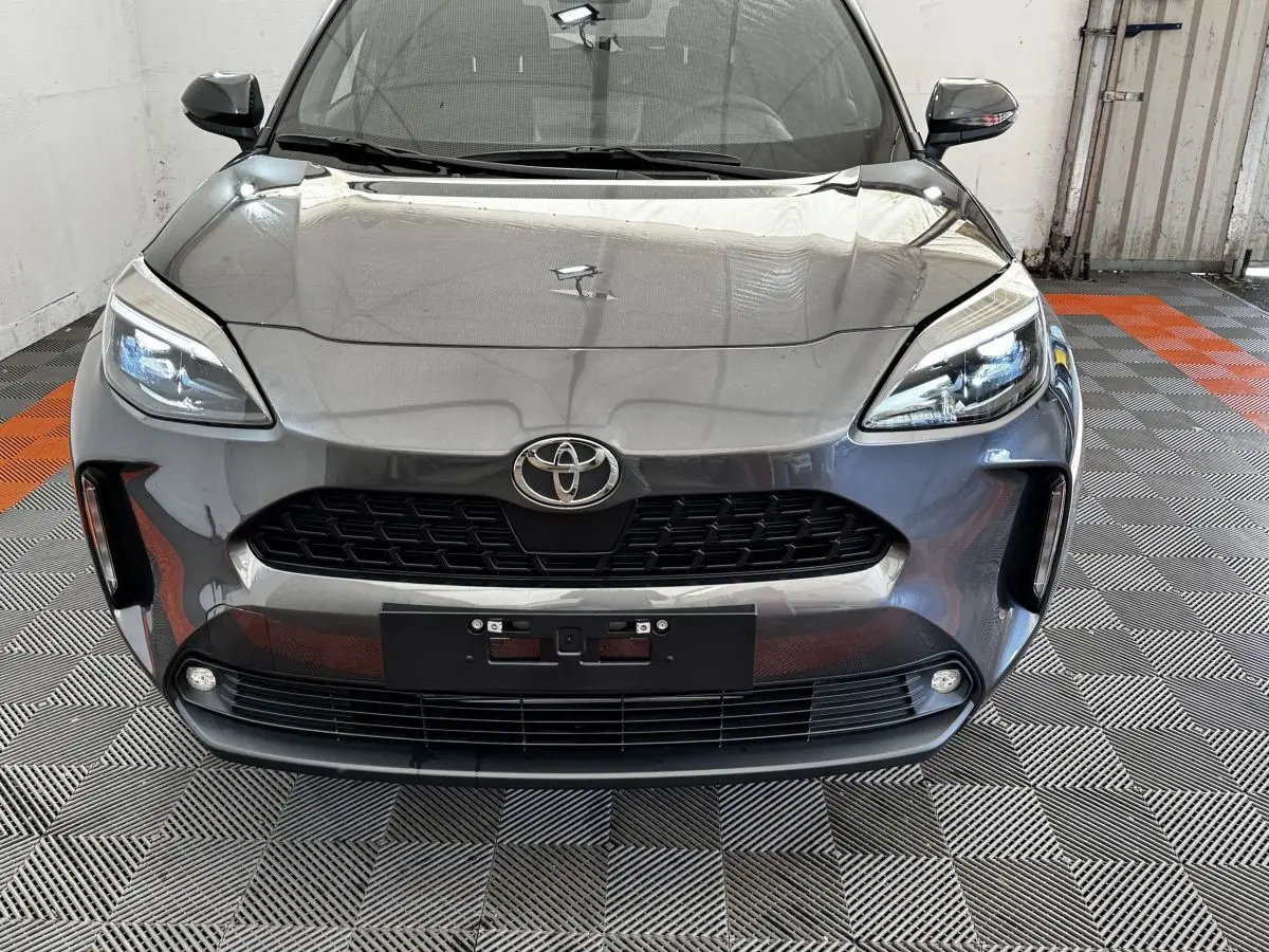 Vue frontale d'une Toyota Yaris Cross 1.5 Hybrid 130h Design Auto gris foncé avec phares LED et calandre noire.