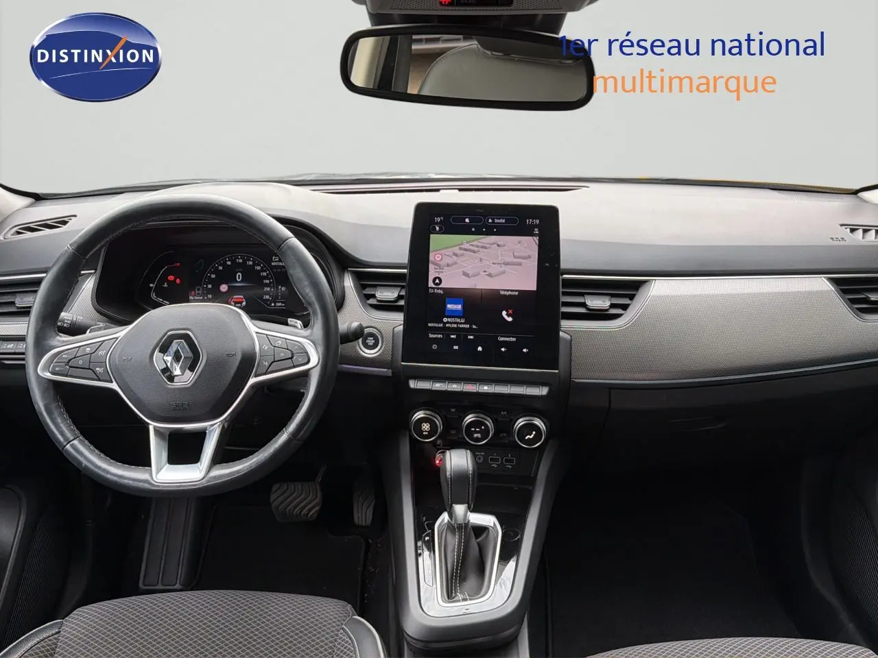 Vue intérieure frontale du tableau de bord gris et noir du Renault Arkana 2022 avec écran tactile central et volant cuir.