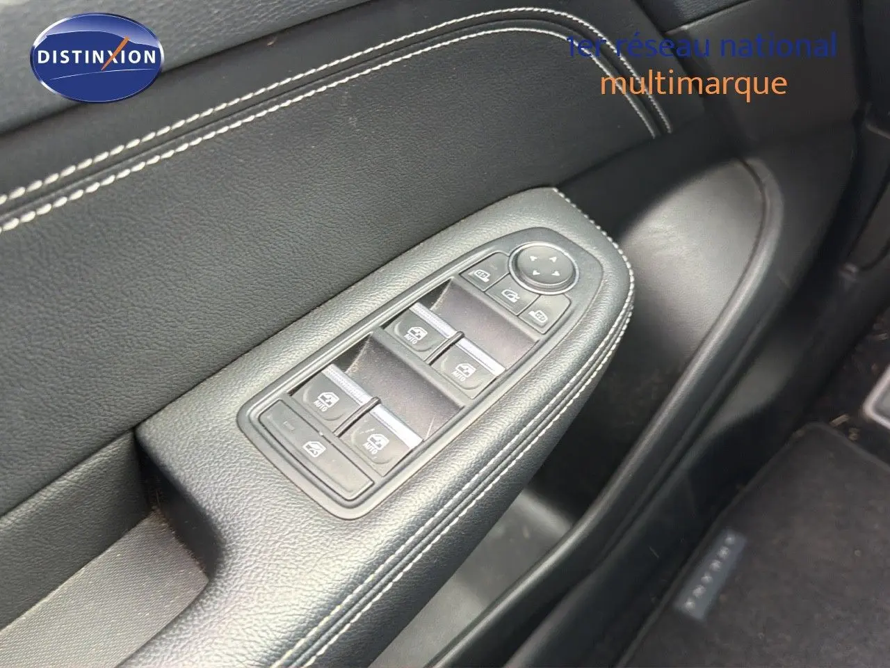 Gros plan sur la commande des vitres électriques côté conducteur en cuir noir avec surpiqûres blanches du Renault Arkana gris.