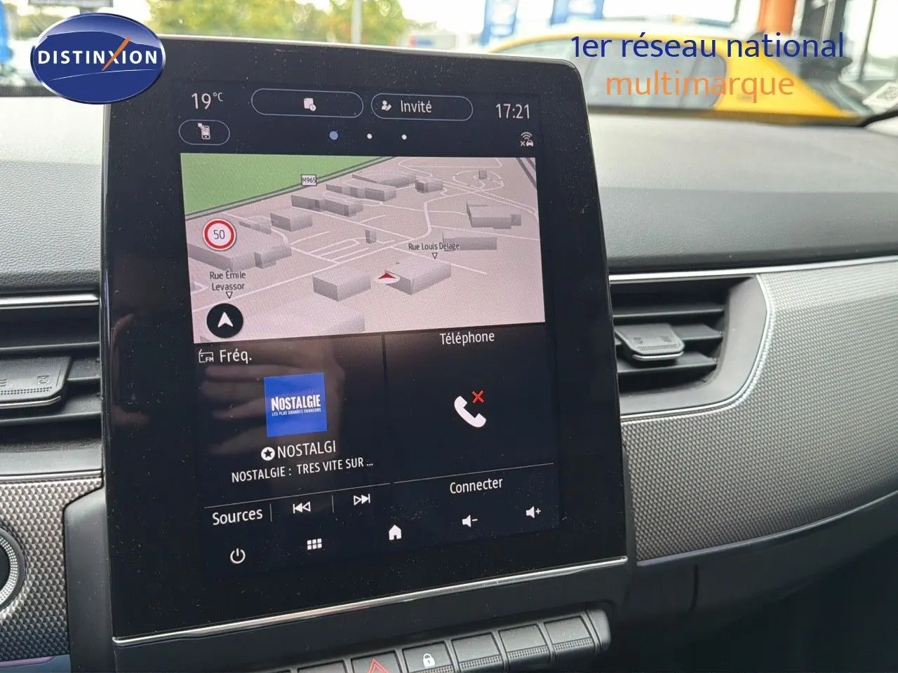 Vue rapprochée de l'écran tactile central du tableau de bord du Renault Arkana gris avec navigation et radio affichées.