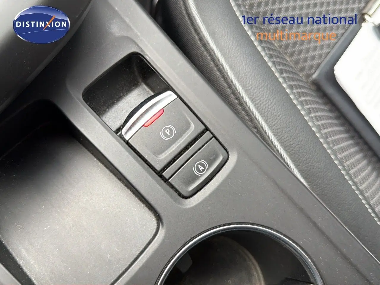 Gros plan sur la console centrale noire du Renault Arkana gris, montrant les boutons de frein à main électrique et d'arrêt automatique.