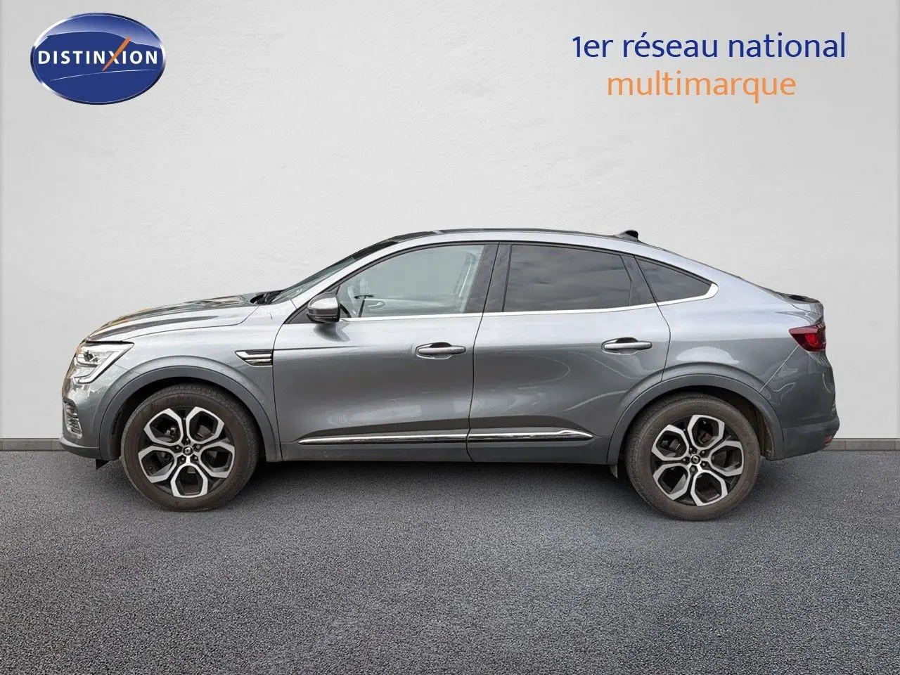 Profil côté gauche d'une Renault Arkana gris métallisé 2022 avec jantes alliage bicolores et lignes fluides.