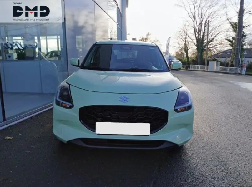 Vue frontale d'une Suzuki Swift 1.2 Privilège Hybrid 2024 en Cool Yellow, avec calandre noire et phares LED allumés.