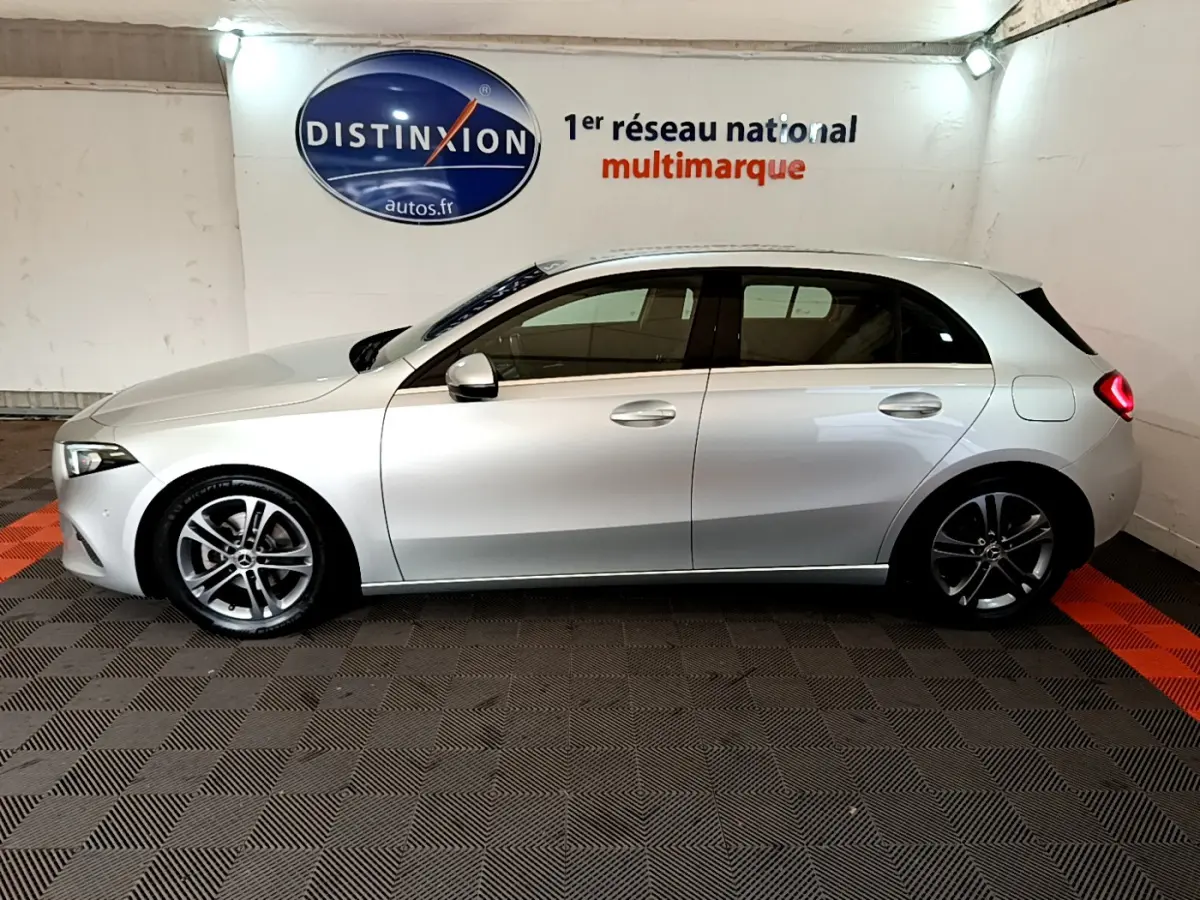 Vue de profil côté gauche d'une Mercedes Classe A A 180 d Business Line gris clair dans un showroom intérieur.
