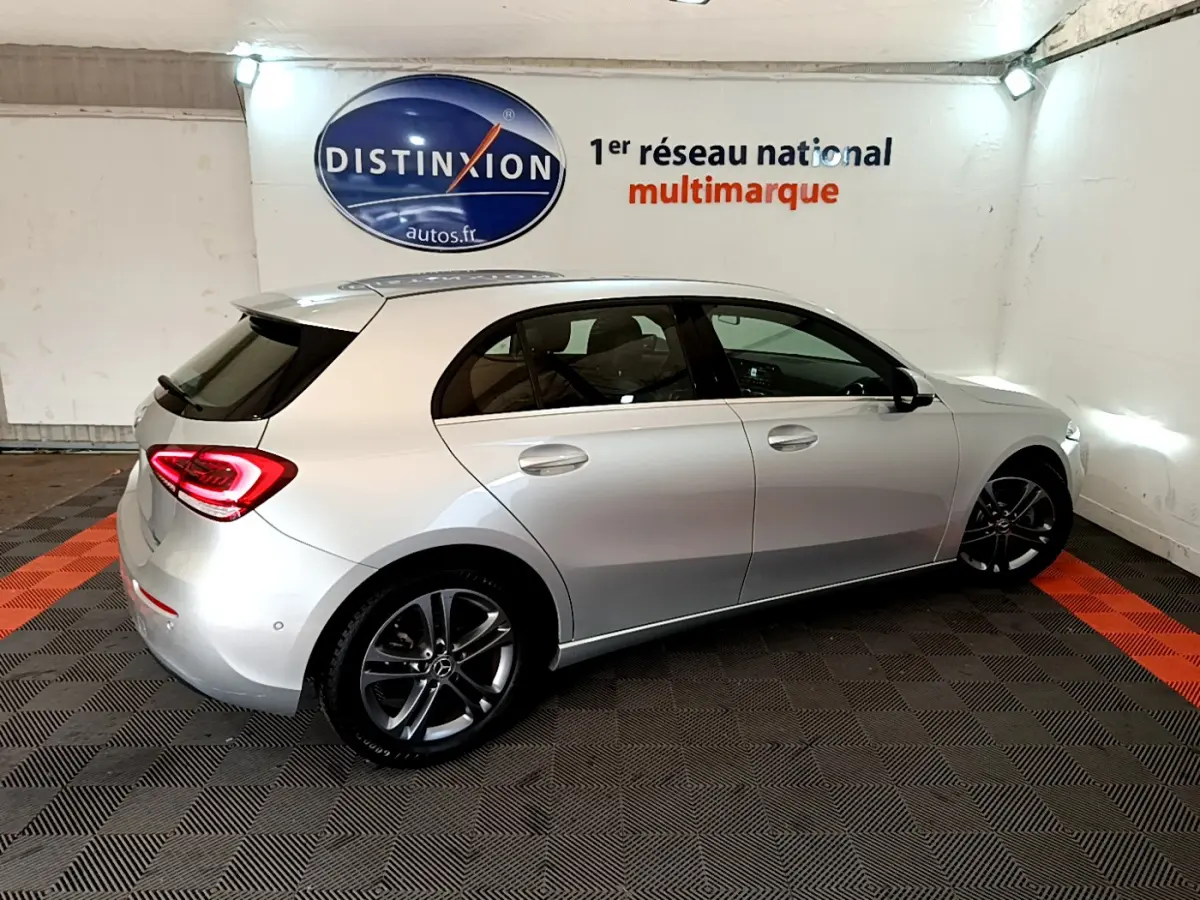 Vue 3/4 arrière droite d'une Mercedes Classe A A 180 d Business Line gris clair dans un showroom intérieur.