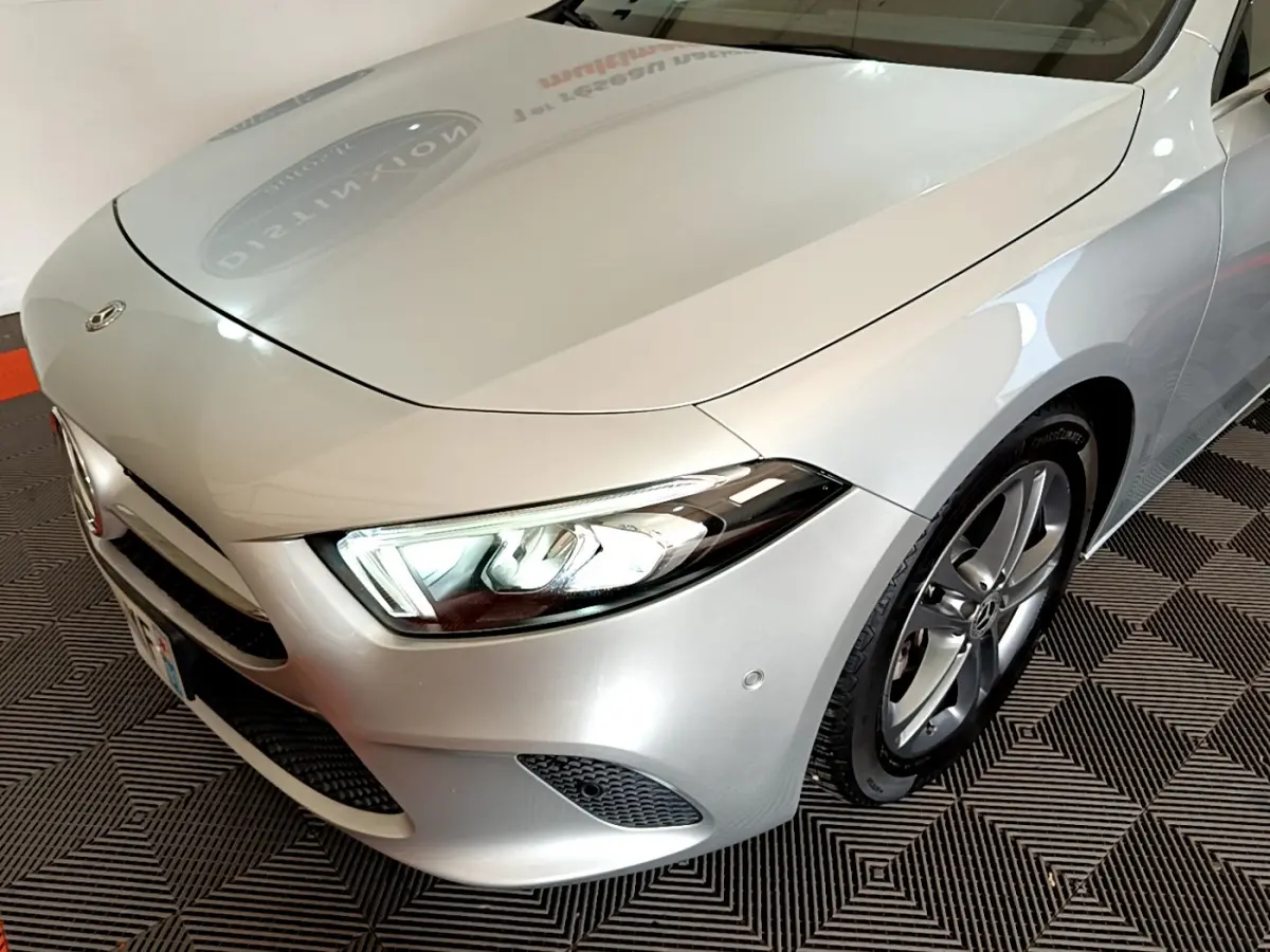 Vue 3/4 avant droit d'une Mercedes Classe A 180 d Business Line gris clair avec phares LED allumés.