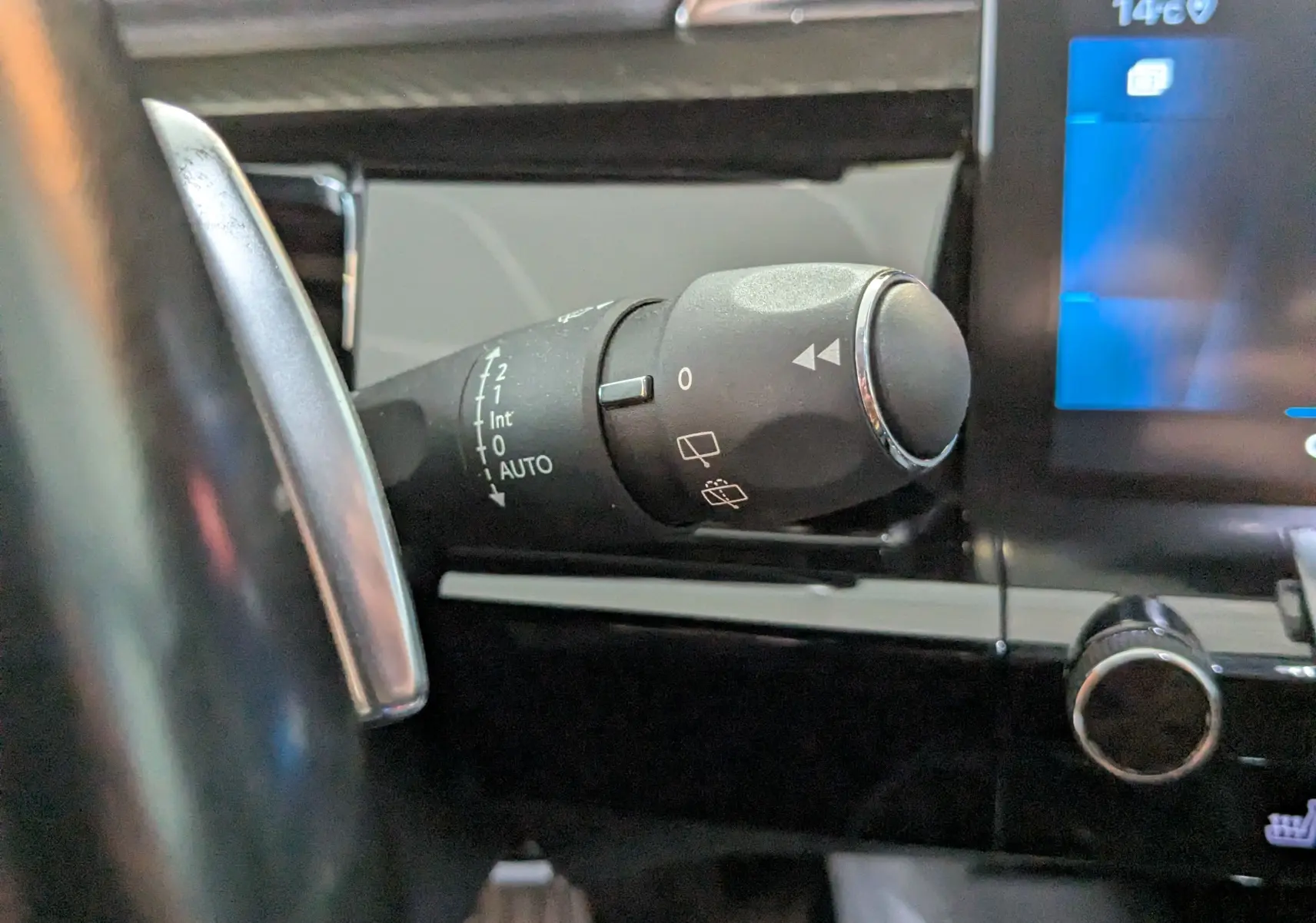 Gros plan sur la manette de commande d’essuie-glace à gauche du volant dans l’habitacle gris du Peugeot 508 SW 2021.