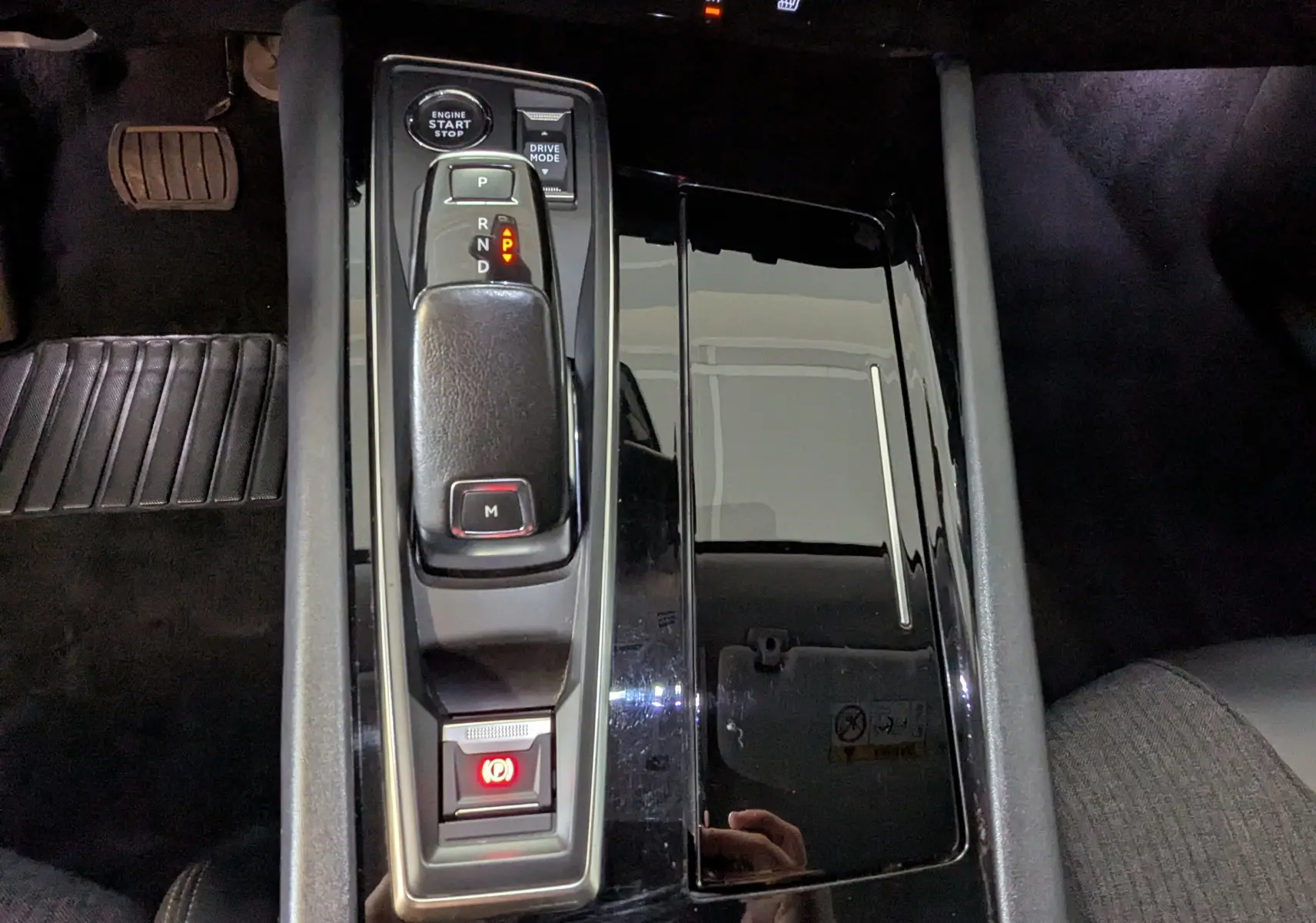 Vue rapprochée de la console centrale noire brillante avec levier de vitesse automatique et bouton start/stop d'une Peugeot 508 SW 2021.