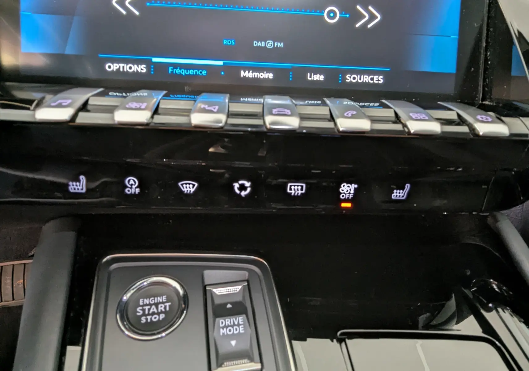 Détail de la console centrale de la Peugeot 508 SW gris 2021, avec boutons de commande et écran tactile en arrière-plan.