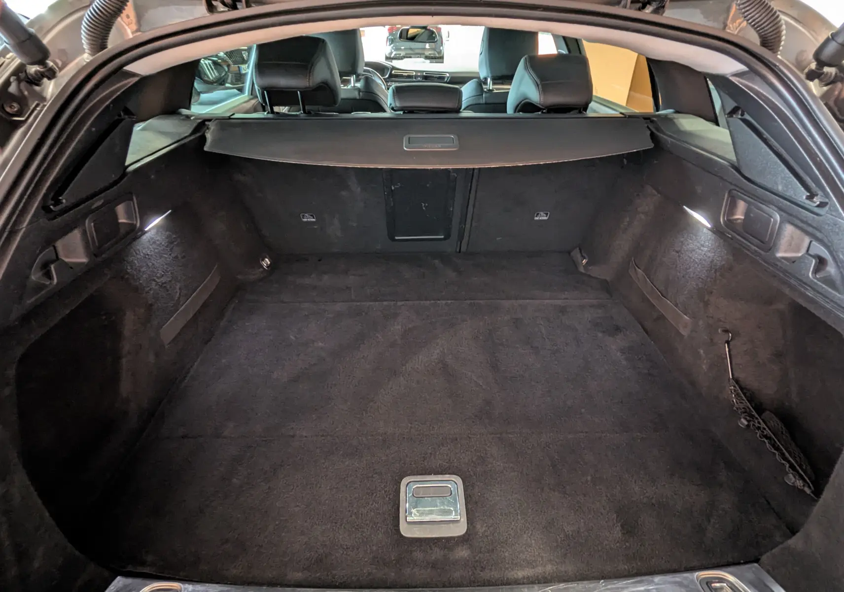 Coffre ouvert vu de l'arrière d'une Peugeot 508 SW gris, montrant un espace de chargement propre et bien éclairé.