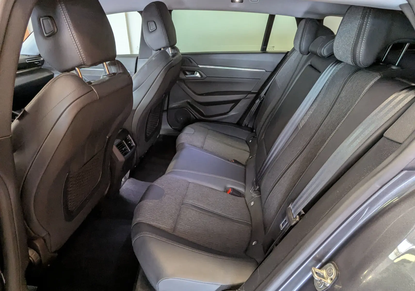 Vue intérieure côté droit des sièges arrière en tissu gris et cuir noir du Peugeot 508 SW gris, version 2021.