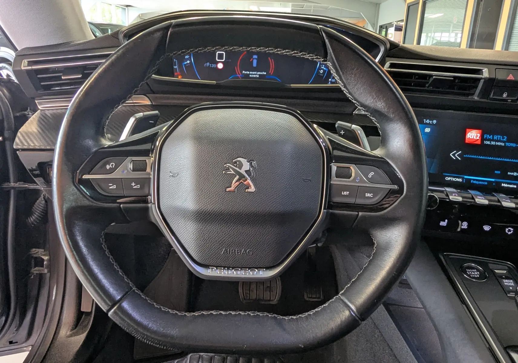 Vue rapprochée du volant cuir noir du Peugeot 508 SW 2021 avec tableau de bord numérique et écran tactile central.