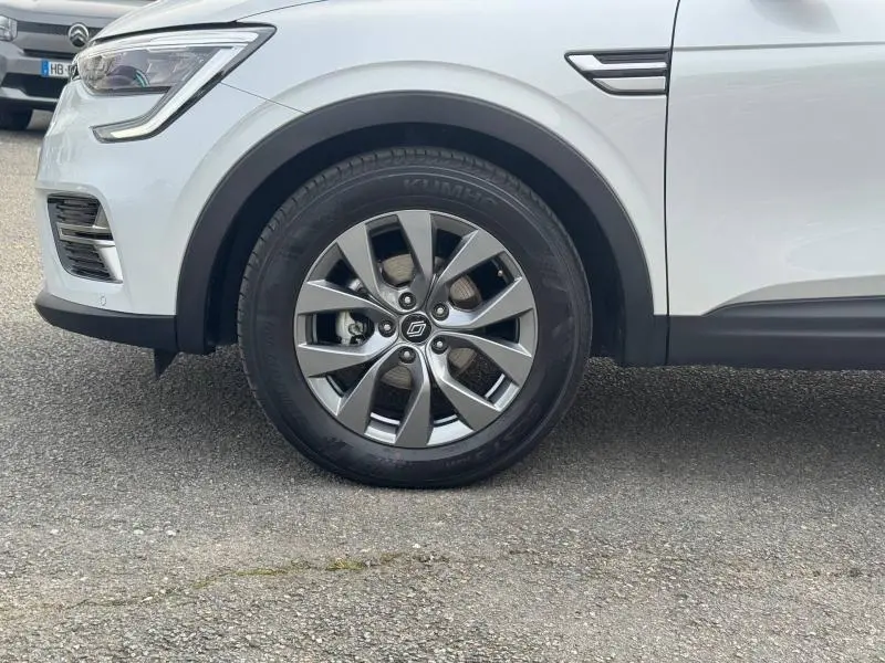 Gros plan sur la roue avant gauche du Renault Arkana blanc 2025, mettant en valeur la jante alliage et le passage de roue noir.