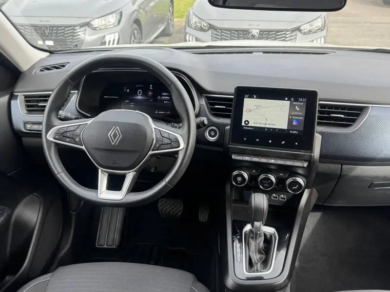Vue intérieure frontale du tableau de bord et volant du Renault Arkana blanc 2025 avec écran tactile et boîte automatique.