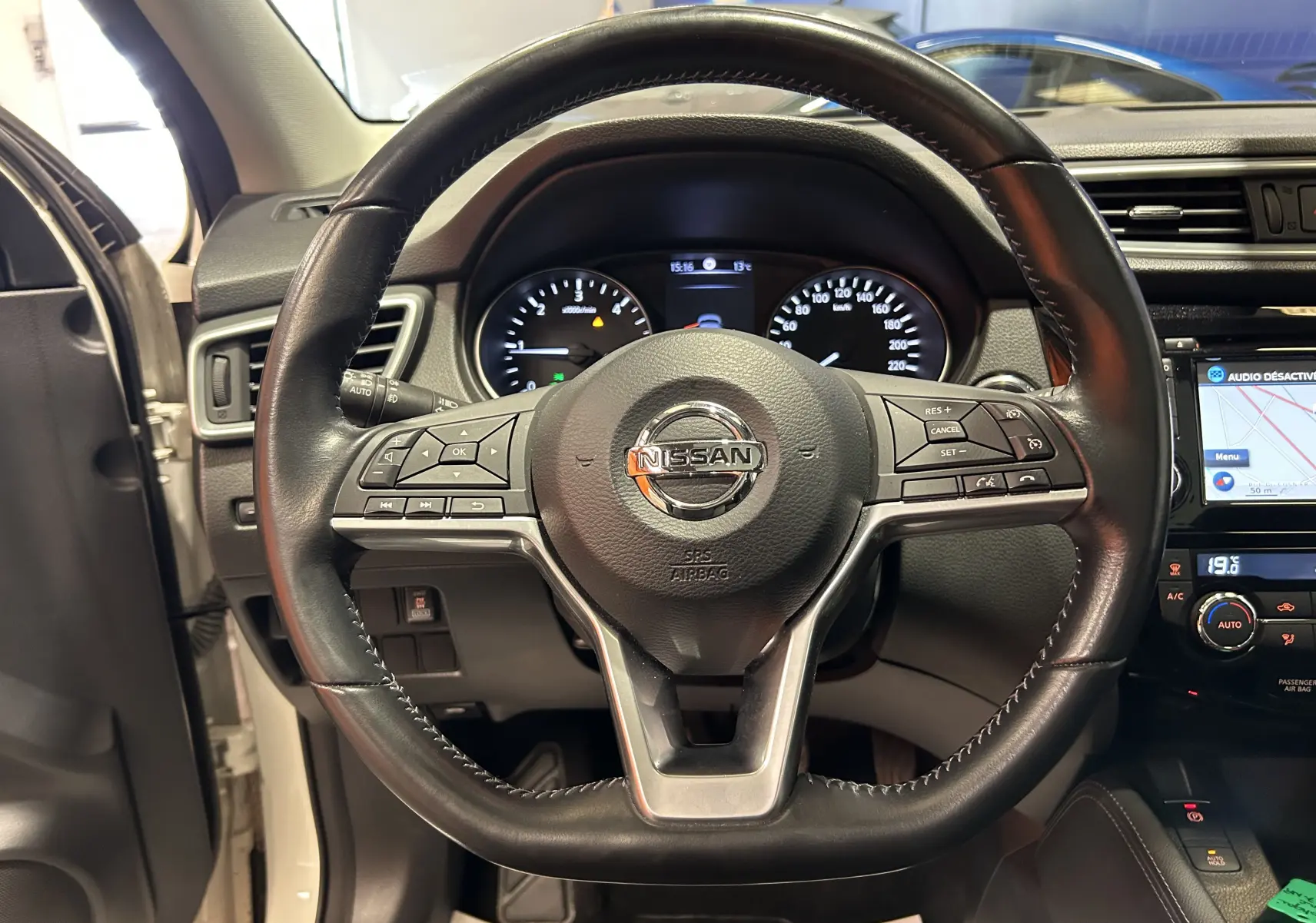 Vue rapprochée du volant cuir noir du Nissan Qashqai blanc 2018 avec tableau de bord et écran tactile visible.