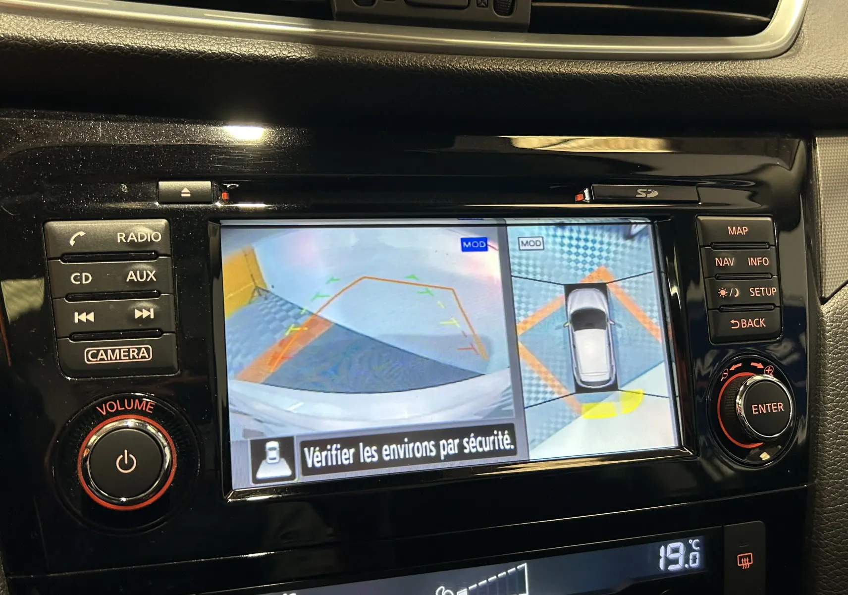 Écran central du Nissan Qashqai blanc montrant la caméra 360° en mode recul avec affichage des aides au stationnement.