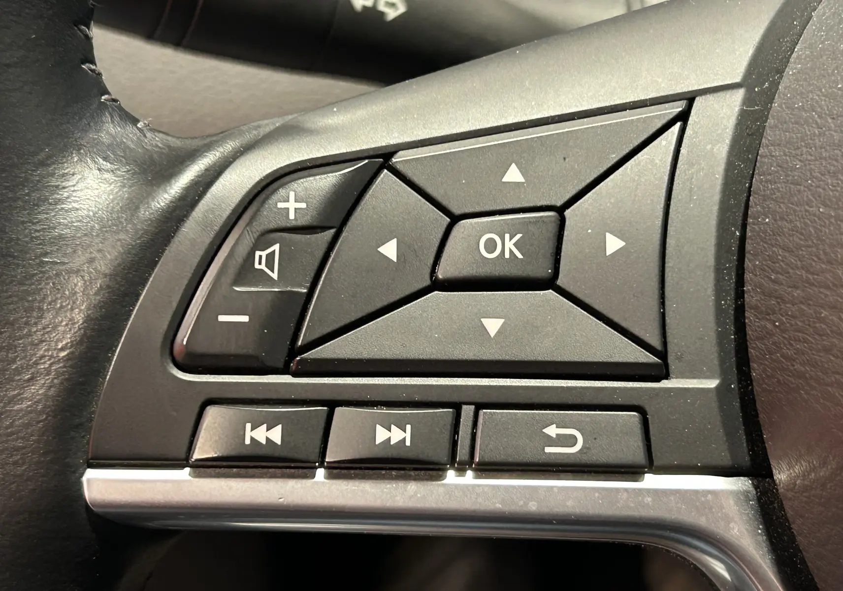 Gros plan sur les commandes multifonctions noires du volant côté gauche du Nissan Qashqai blanc 2018.