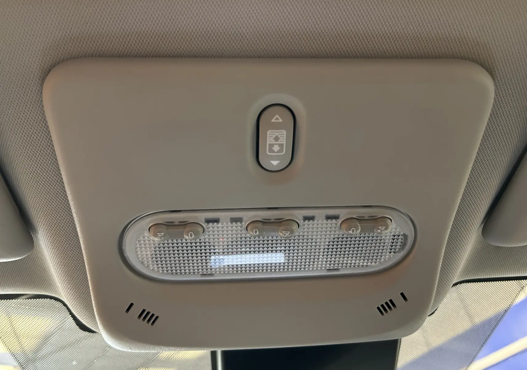 Plafonnier intérieur beige avec commandes d’éclairage et ouverture du toit panoramique sur Nissan Qashqai blanc, vue de dessous.