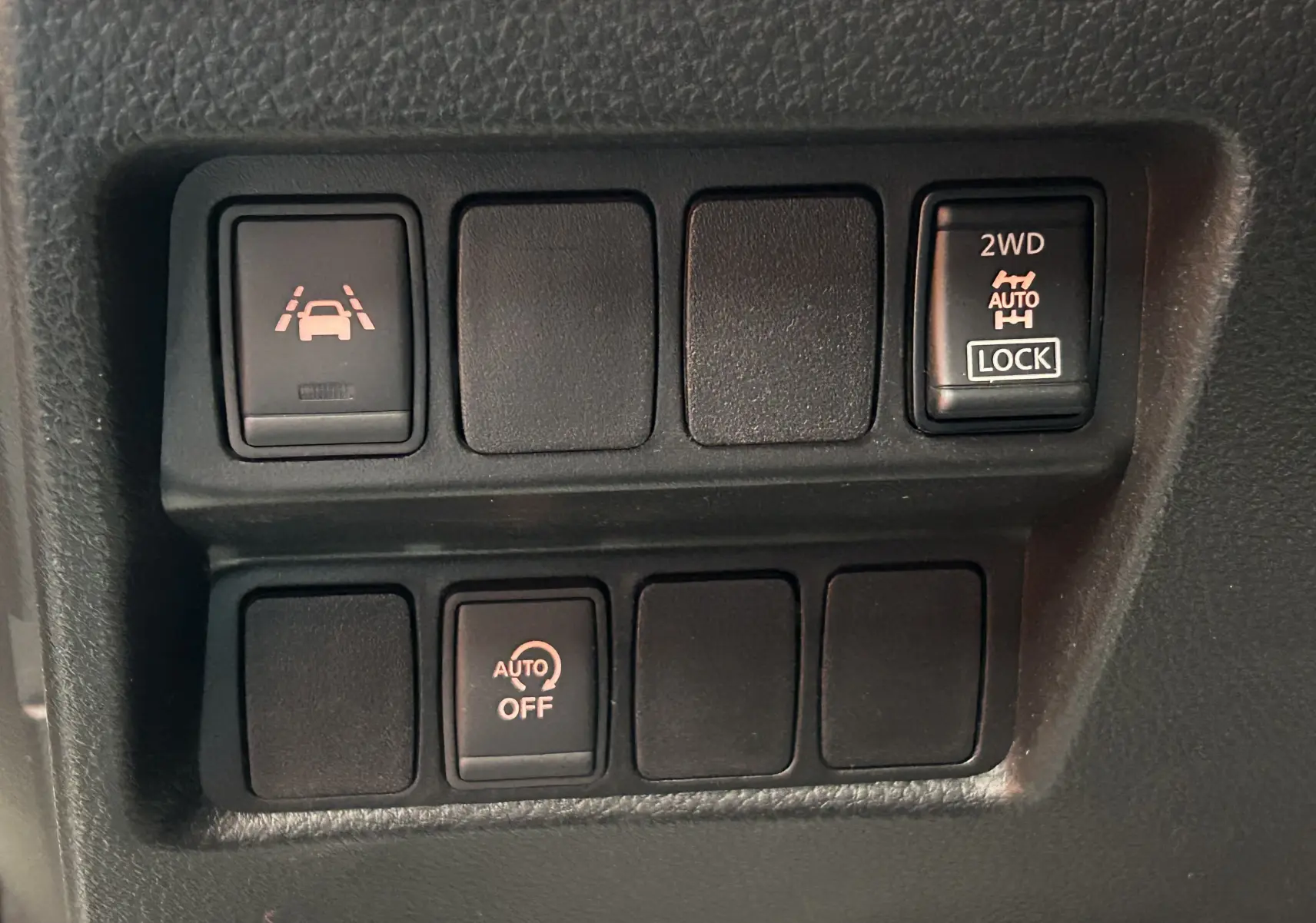 Gros plan sur les boutons de commande du tableau de bord du Nissan Qashqai blanc, avec fonction 4x4 et assistance à la conduite.